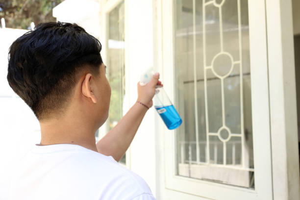 Asian Man Spraying Cleaning Kits to the Window