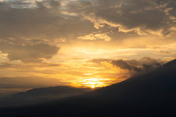 istock This image captures a beautiful sunset over a mountain range. The sky is a vibrant orange and yellow, with cloudy sky. The sun is setting behind the mountains, casting long shadows over the landscape. 2172154280
