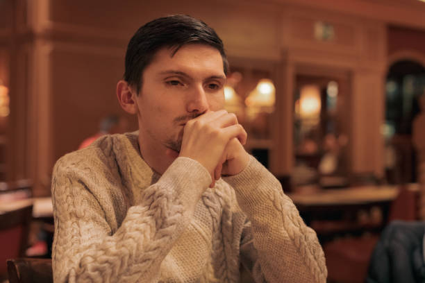 Pensive young man sitting at the table and looking away