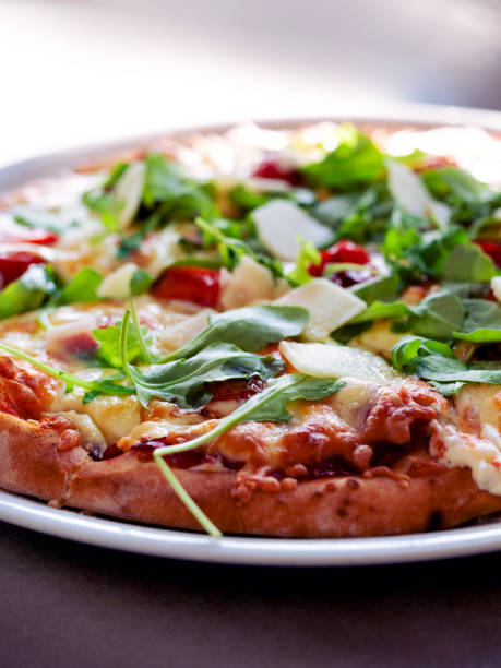 istock Freshly made baked pizza topped with arugula, cherry tomatoes, and cheese on a dining table 2172154865