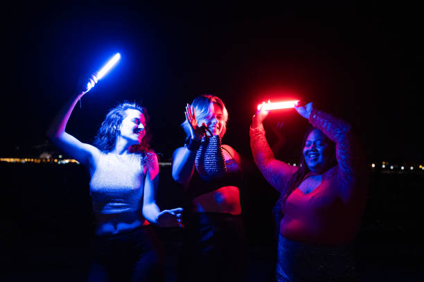 istock Cool women dancing with laser swords at beach party 2172170271