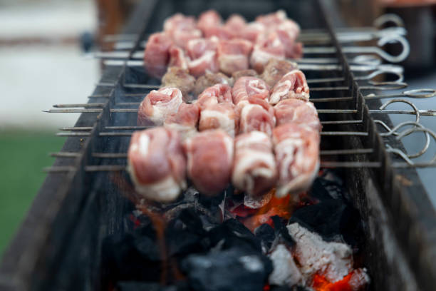 Barbecue on the grill. Grilled kebab cooking on metal skewer, close up