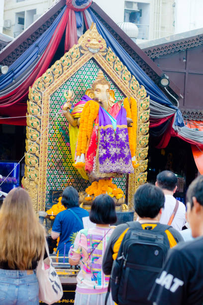 Decorated Ganesha statue and shrine  in Bangkok. Shrine is located at Ratchadaphisek Road in Huai Khwang and is near night market and popular place for prayers both for thai people and asian tourists.  People  are praying and placing incense sticks and other spiritual gifts. Around standing Genesha is a golden frame