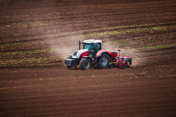 istock Farmer with tractor seeding crops at field 2172182274