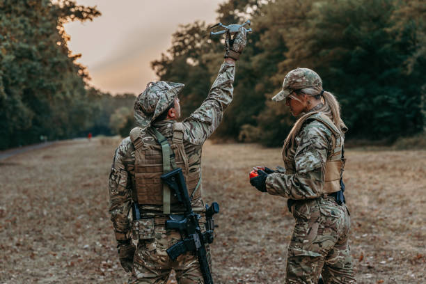 Military Training: Special Ops Forces Pair of armed female and male soldiers operating surveillance drone woman stealth stock pictures, royalty-free photos & images