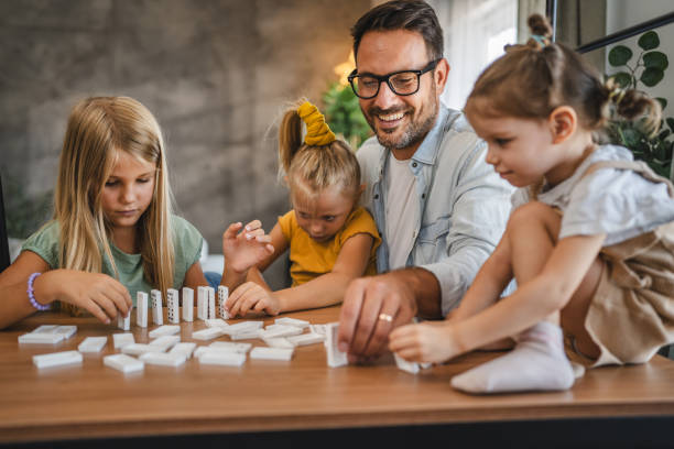 istock Single father play dominoes with his three young daughters at home 2172183466
