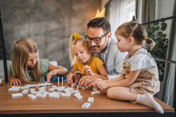 istock Single father play dominoes with his three young daughters at home 2172183468
