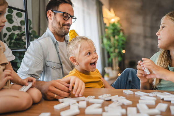 istock Single father play dominoes with his three young daughters at home 2172183779