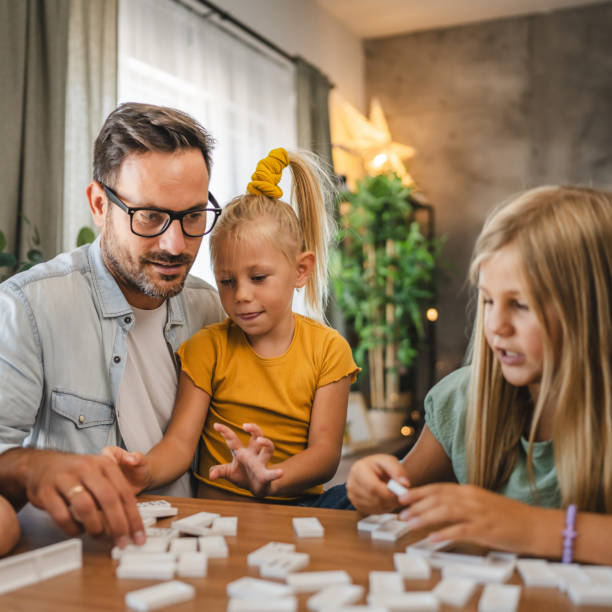 istock Single father play dominoes with his three young daughters at home 2172183833