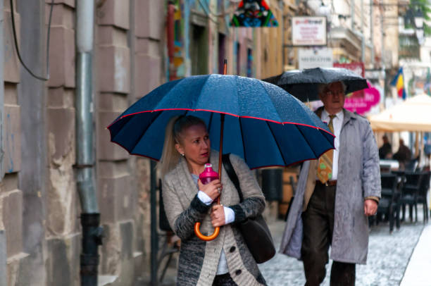 Timisoara, Romania - May 03, 2016: Woman walking on the street in the rain with an umbrella in hand. Real people.