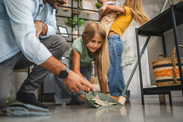 istock Daughters clean broken vase with a broom and dustpan in living room 2172186150