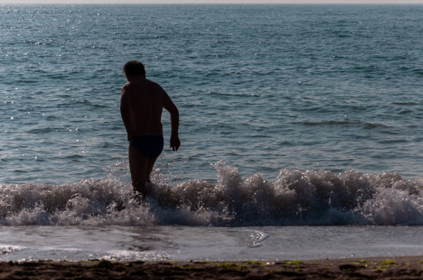 Silhouette of people walking on the beach. Unrecognisable people. Focus on the sea