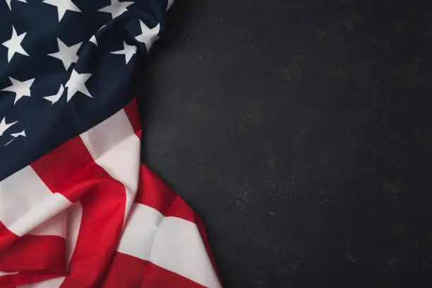 A red and white American flag is draped over a black background A red and white American flag is draped over a black background