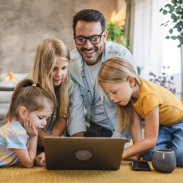 istock Father and three daughters enjoy time together with a laptop screen 2172192056