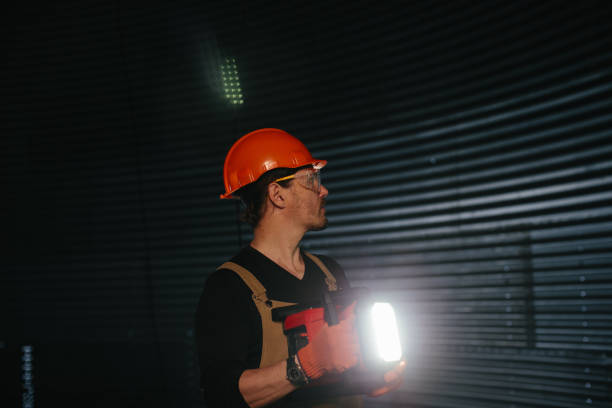 istock Male worker in safety helmet with flashlight in hands inside storage tank. Inside the grain silo. 2172206918