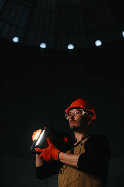 istock Male worker in safety helmet with flashlight in hands inside storage tank. Inside the grain silo. 2172206929