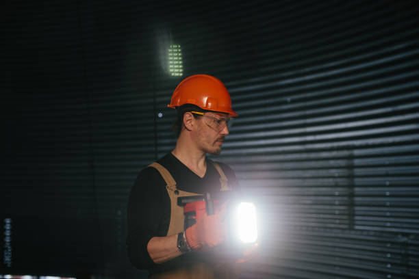 istock Male worker in safety helmet with flashlight in hands inside storage tank. Inside the grain silo. 2172206930