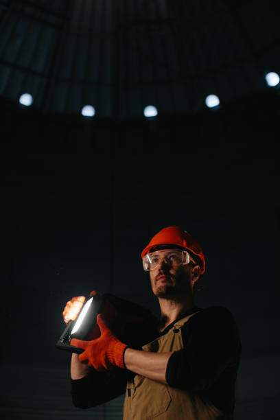 istock Male worker in safety helmet with flashlight in hands inside storage tank. Inside the grain silo. 2172206946