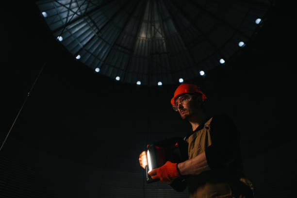 istock Male worker in safety helmet with flashlight in hands inside storage tank. Inside the grain silo. 2172206947