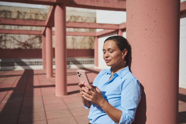 istock Woman relaxing outdoors leaning against a pillar while using a smartphone on a sunny day 2172211126
