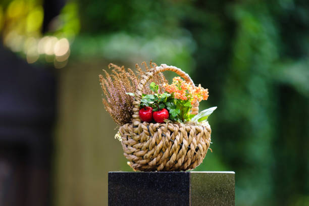 woven basket with flower decoration on a gravestone of a cemetery in front of a blurred background