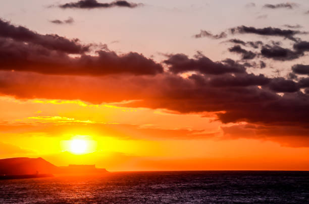 The sky is filled with clouds and the sun is setting