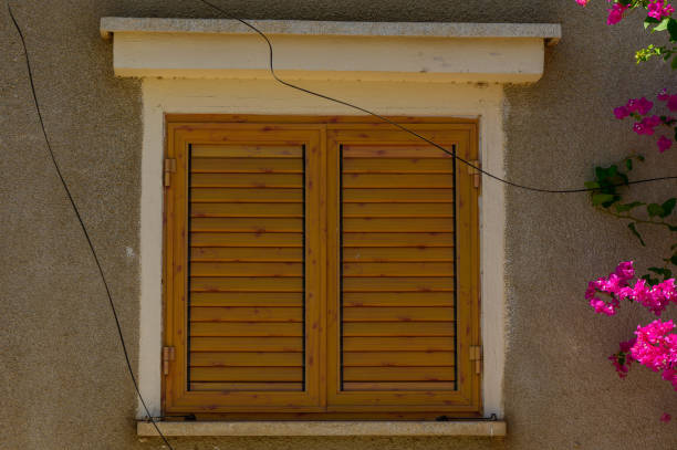 window covered with brown wooden shutters on the wall of boards
