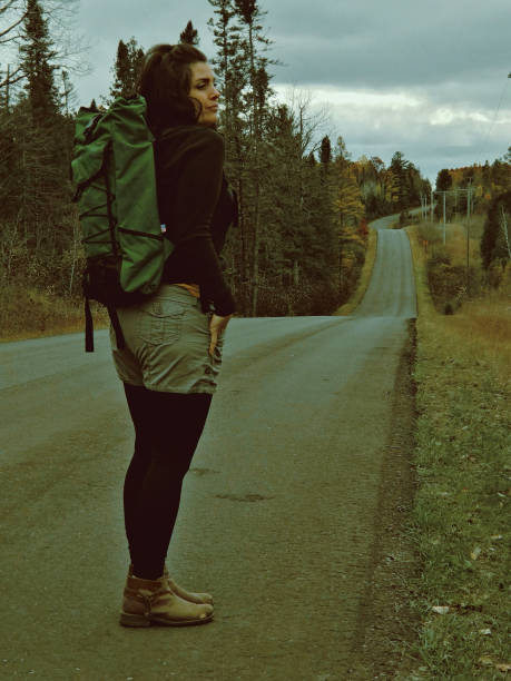 istock Adventurous woman backpacking on a rural road. 2172235004
