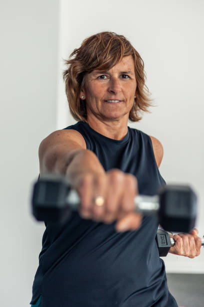 istock vertical Elderly woman focused punching towards camera with dumbbell during body combat class 2172235346