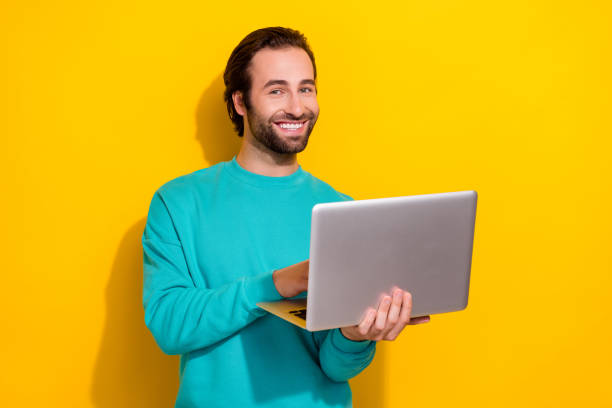 istock Photo of cheerful good mood smiling it coder professional programmer hold his samsung laptop app developer isolated on yellow color background 2172237064