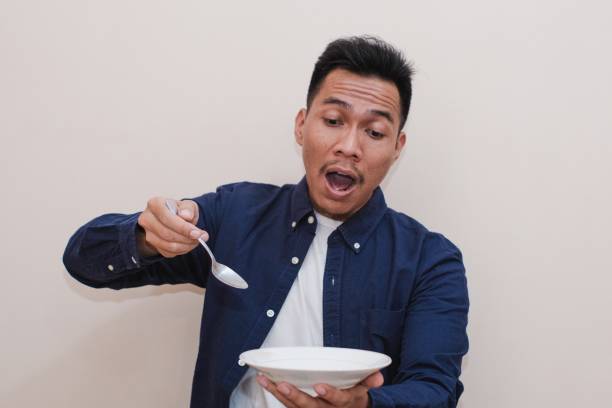 istock A Southeast Asian man happy wearing a blue shirt while holding an empty plate and spoon with happy and excited expression 2172242002
