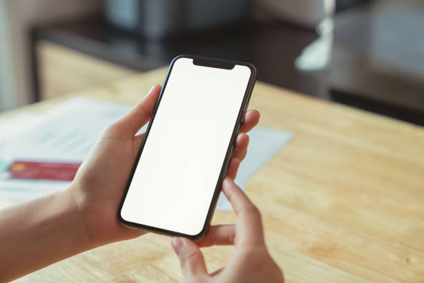 istock Hand holding black smartphone with blank screen on wood background. 2172282835