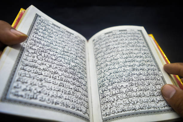 istock Open Quran book with golden edges held by hand, Arabic script visible, symbolizing Islamic faith and spirituality. Arabic word translation:The Holy Al Quran (holy book of Muslim) 2172288583
