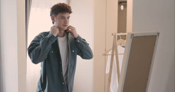 Man Putting on Jacket in Front of Mirror.