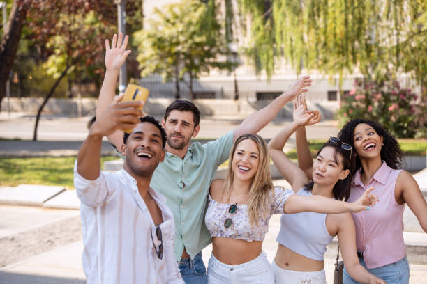 istock Five friends happily taking a selfie outdoors, smiling and waving in a playful pose. 2172297738