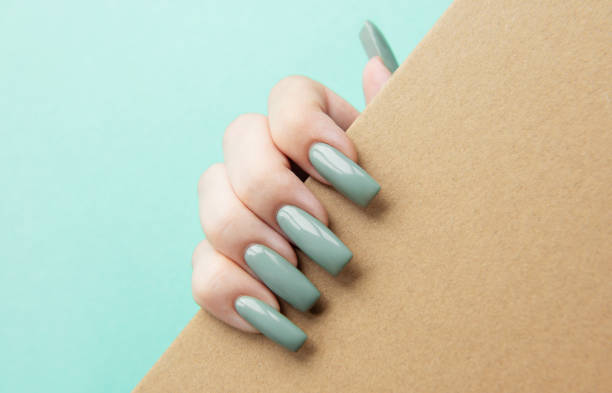 istock Hand holding a brown envelope with long green nails against a light blue background 2172301628