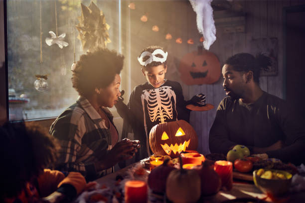 istock Black family looking inside of illuminated Jack O' Lantern on Halloween. 2172307143