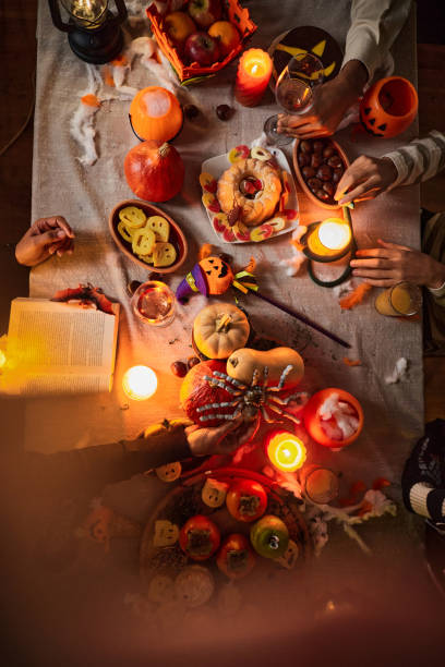Above view of unrecognizable people at dining table on Halloween.