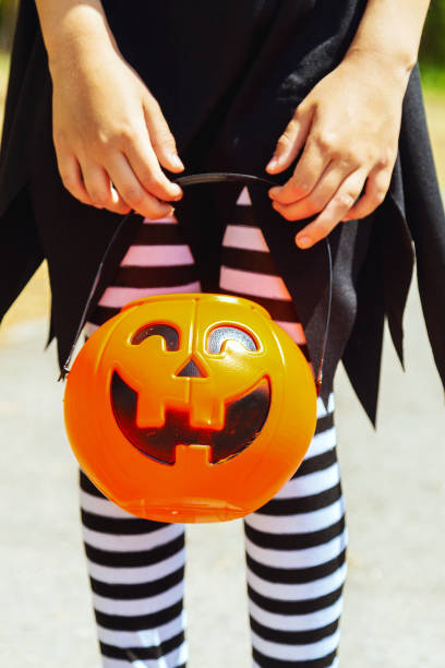 istock Closeup of unrecognizable child holding Halloween basket shaped as Jack o lantern while trick or treating, copy space 2172309078