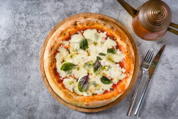 istock Four cheese neapolitan pizza on wooden cutting board on stone table 2172311380