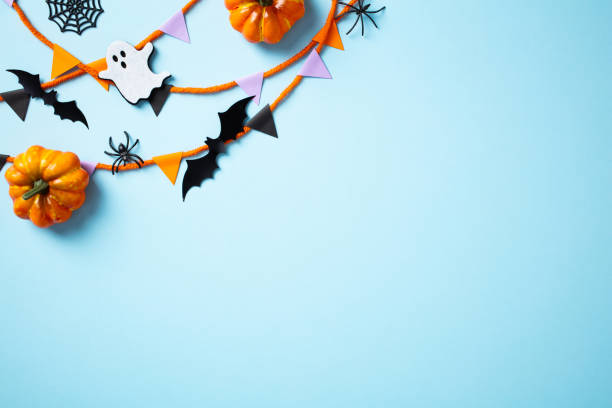 istock Halloween party decorations on blue background. Flat lay composition with pumpkins, garland, bats, ghosts. Happy Halloween greeting card design. 2172312769