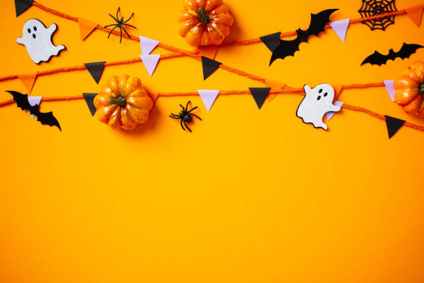 istock Halloween frame with decorations, paper garland, pumpkins, ghosts, spiders on orange background, view from above. Happy Halloween greeting card design, poster template. 2172314046