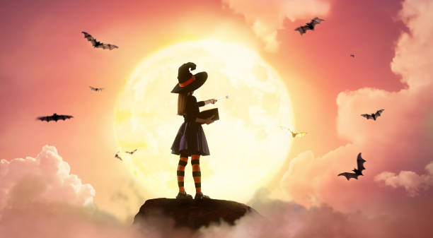 Happy little girl in witch costume at Halloween. Kid on moon sky background.