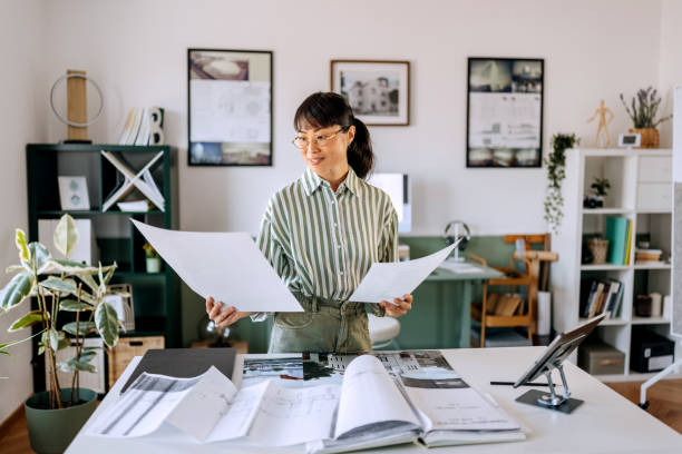 istock Beautiful female architect analysing blueprints at her home office 2172317354