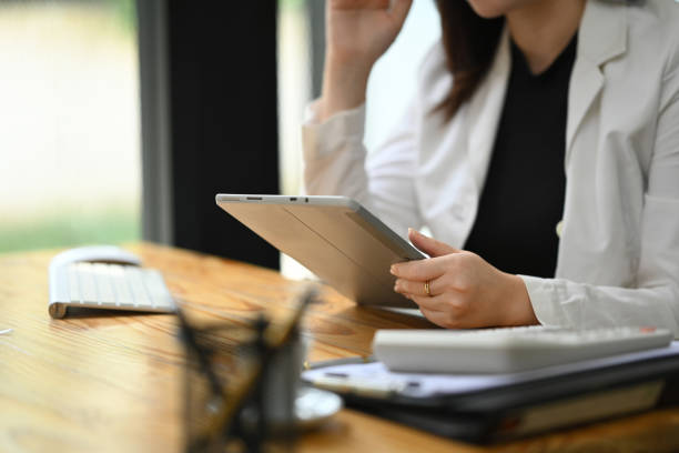 istock Focused professional businesswoman in white suit using digital tablet at modern workplace 2172318485