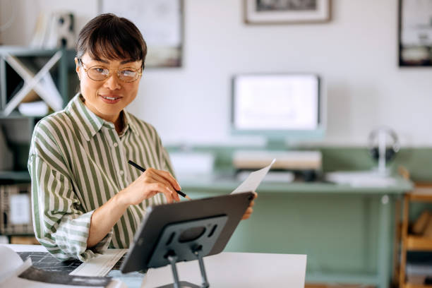 istock Smiling beautiful woman using digital tablet while working at home office 2172318493