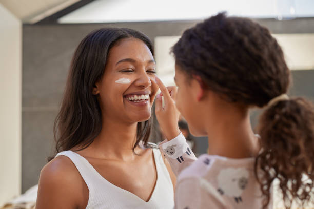 istock Child applying cream to mother face during morning routine 2172318842