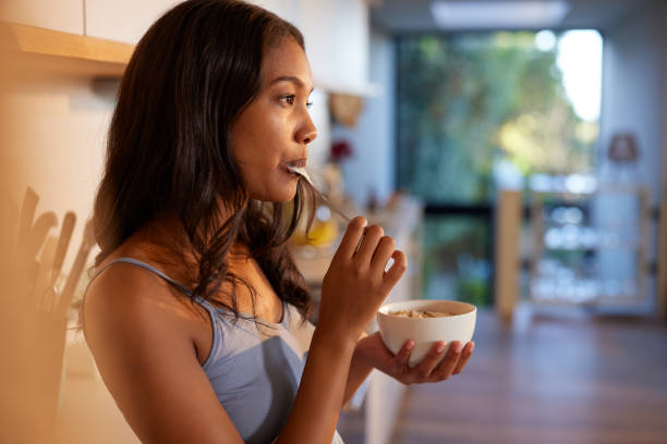 Thoughtful beautiful woman having breakfast with yogurt
