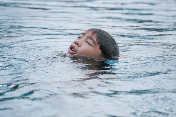 Boy floating on the surface of the water in a swimming pool