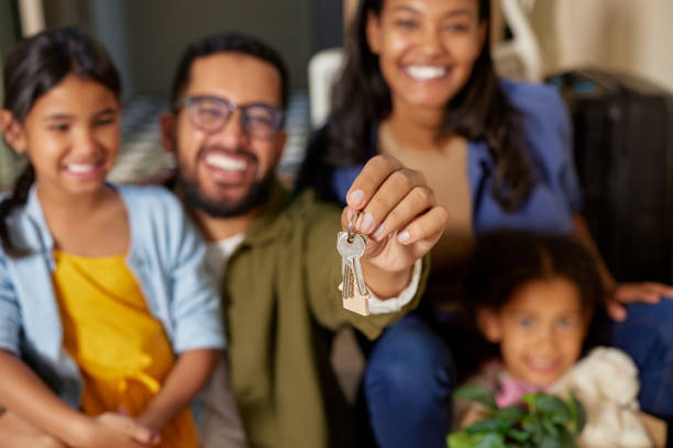 Happy man and family holding new house keys Close up of happy father hands holding new house keys while sitting with family. Happy family excited on purchasing new house with her daughters. Beautiful hispanic couple feeling excited to shift to new house. happy family with key of their new house stock pictures, royalty-free photos & images
